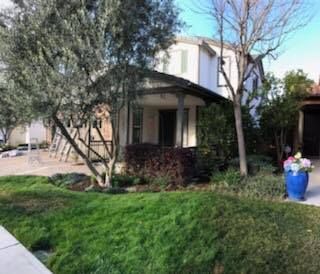 A house with a lush green lawn and trees in front of it.