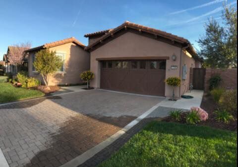 A house with a brown garage door and a brick driveway