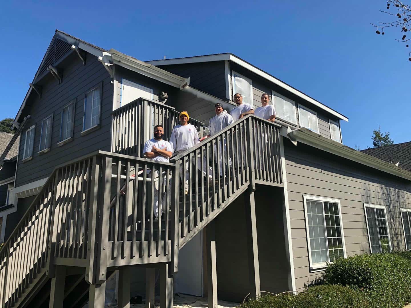 A group of people are standing on a balcony of a house.