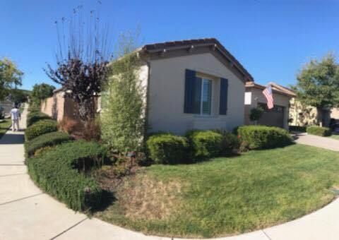 A house with a lush green lawn and bushes in front of it.