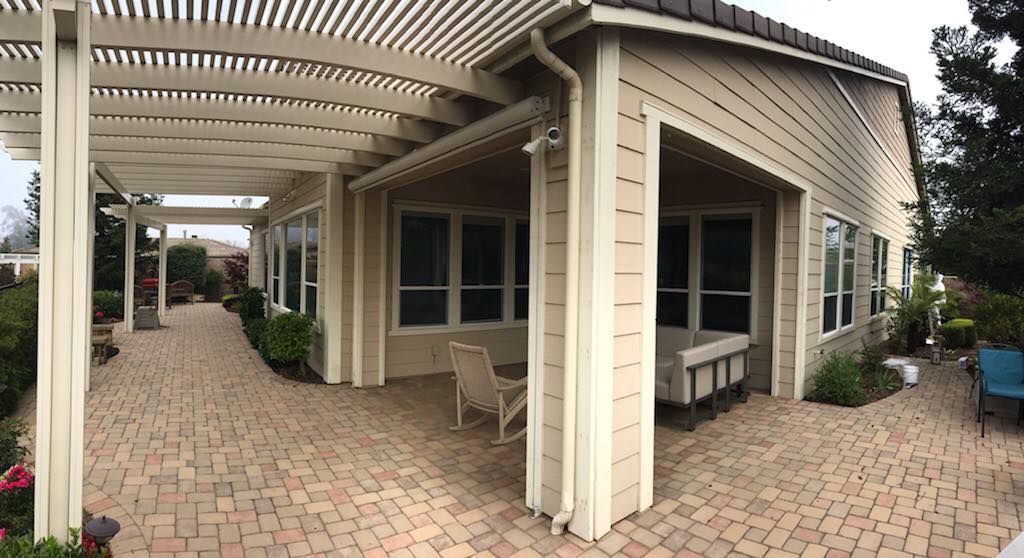 A large house with a pergola and a brick walkway leading to it.