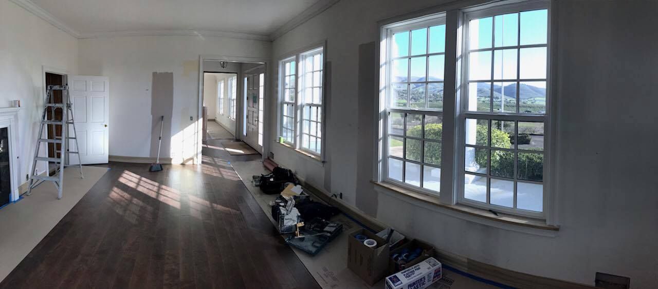 A large empty room with lots of windows and hardwood floors.