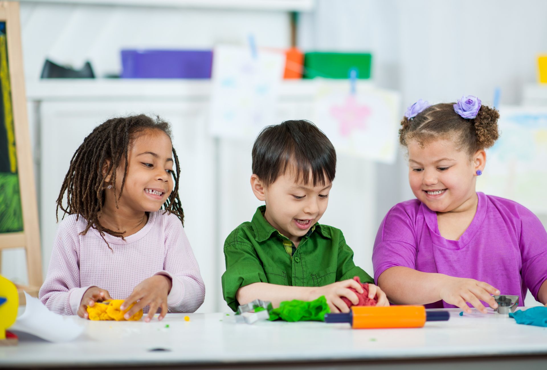 Children shaping colourful clay at a classroom activity table. Children shaping colourful clay at a classroom activity table.