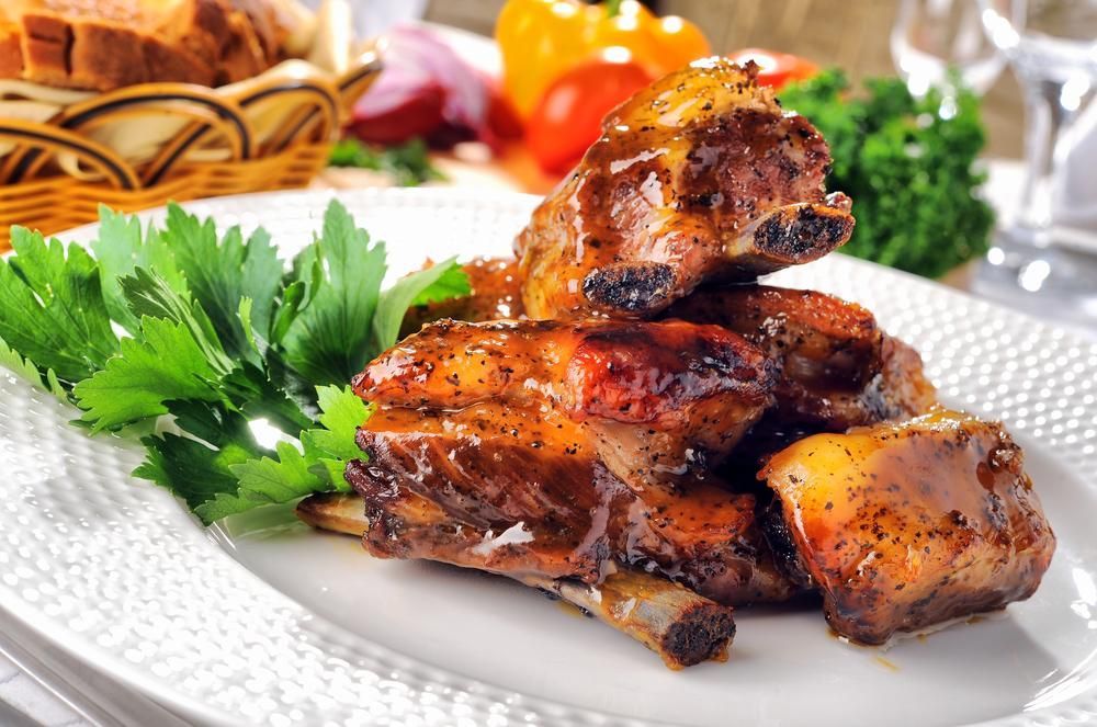 A White Plate Topped with Ribs and Parsley on A Table — Gungahlin Kebab and Pizza in Gungahlin, ACT