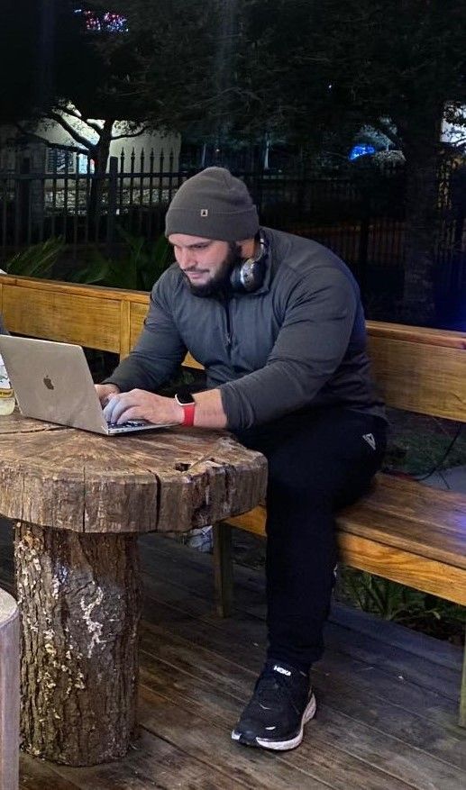 A man is sitting on a bench using a laptop computer.