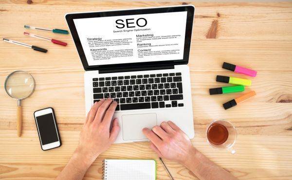 A person is typing on a laptop computer at a wooden desk.