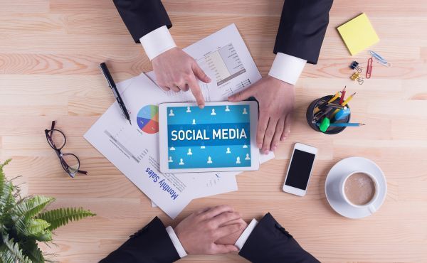 A man is pointing at a tablet with the word social media on it.