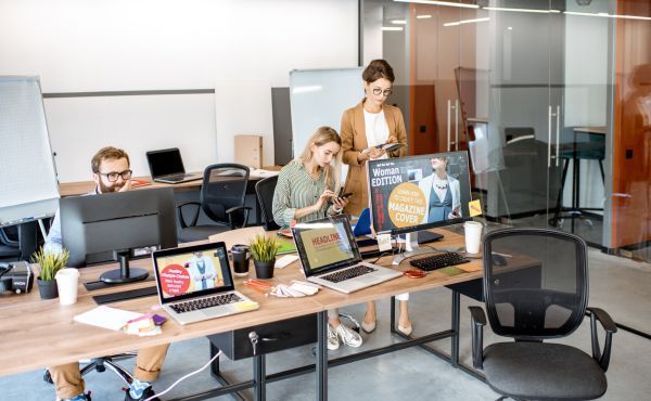 A group of people are sitting at desks in an office.