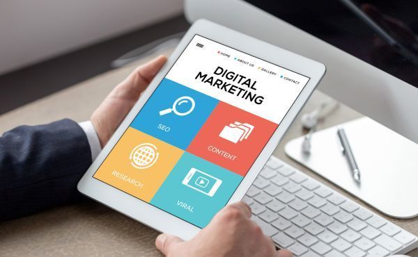 A person is holding a tablet with a digital marketing website on it.