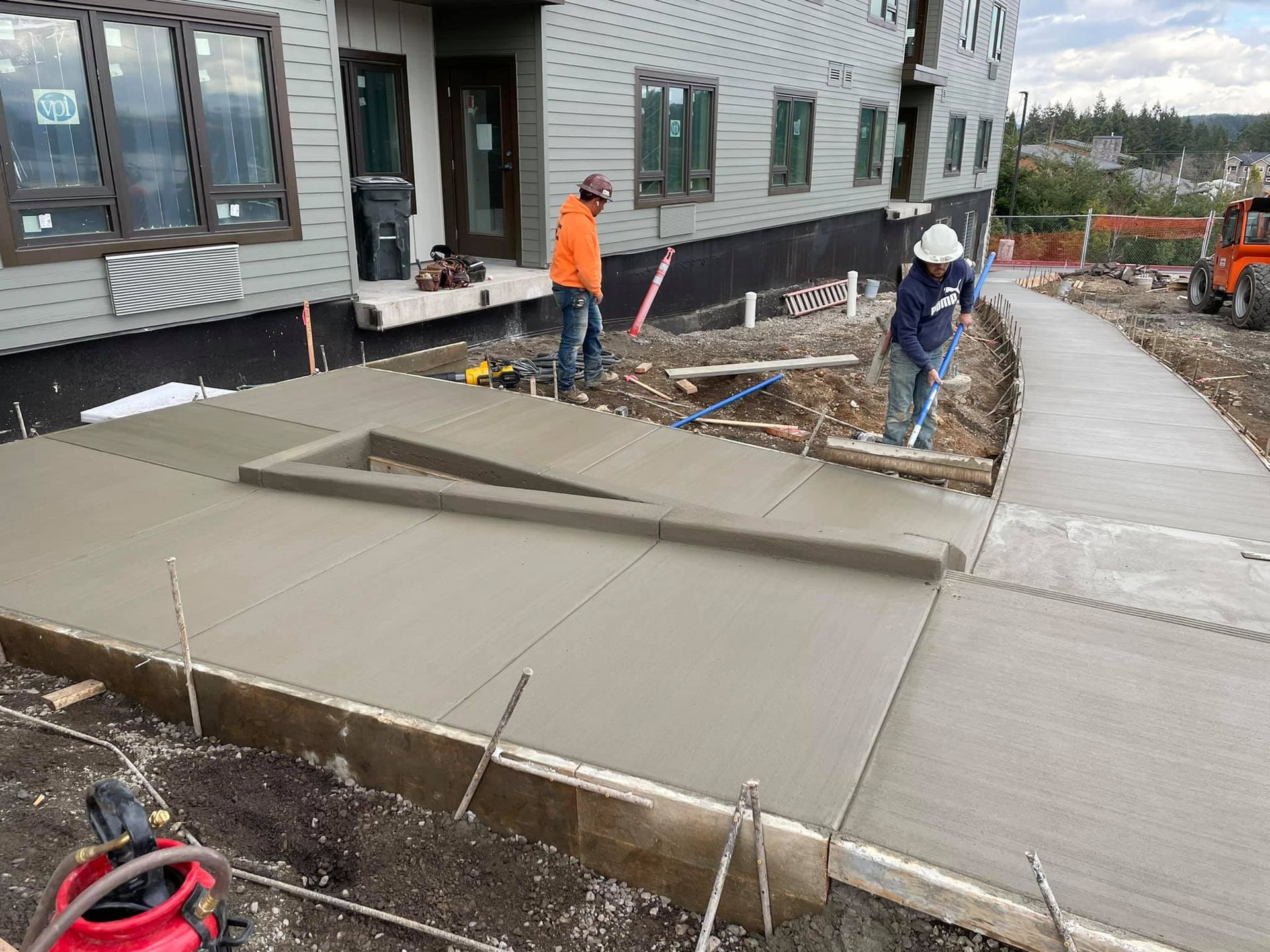 Two construction workers are working on a sidewalk in front of a 
building in Vancouver Washington