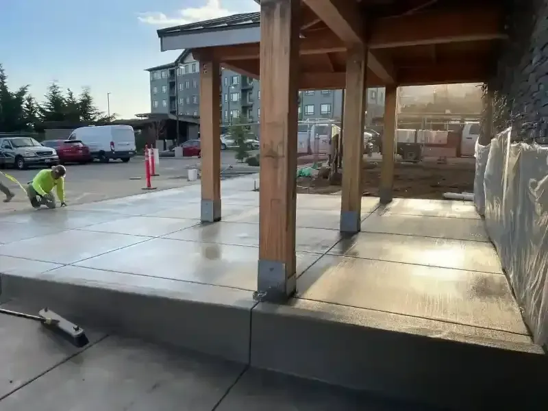A man is working on a concrete walkway under a wooden structure in Vancouver Washington.