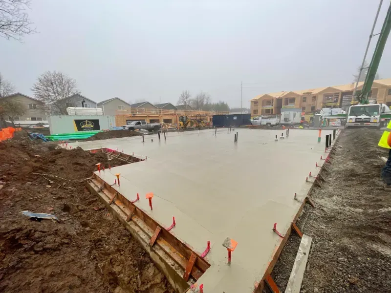 A large concrete slab is being poured on a construction site.