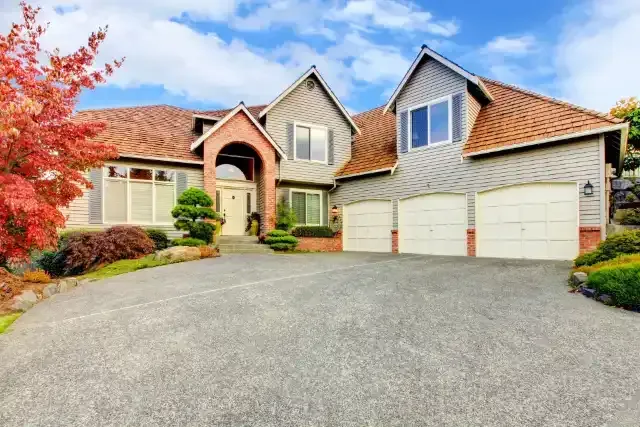 A large house with a garage and a driveway on a sunny day.