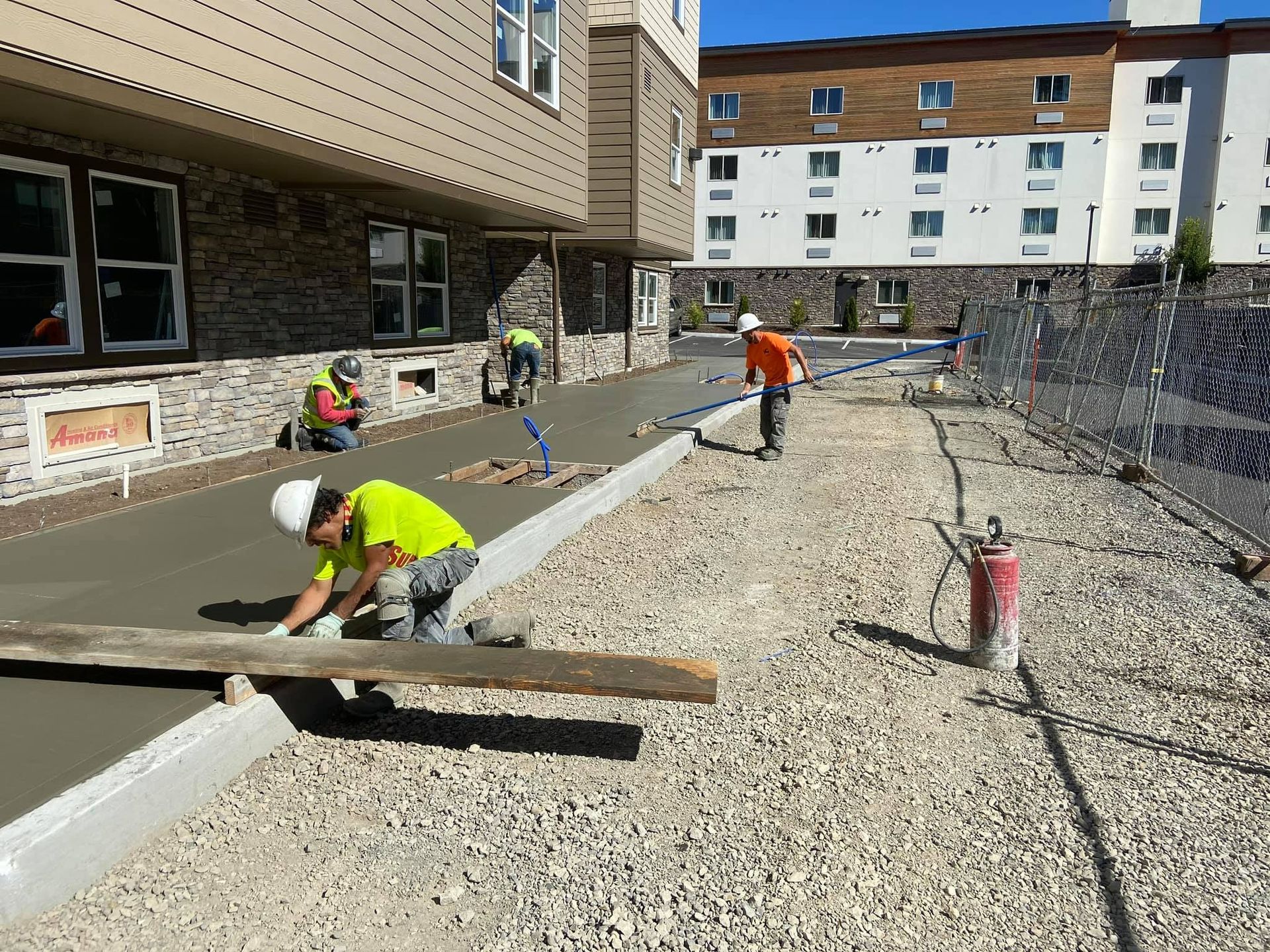 A group of construction workers are working on a sidewalk in front of a building in Vancouver, WA by NAVA Concrete LLC