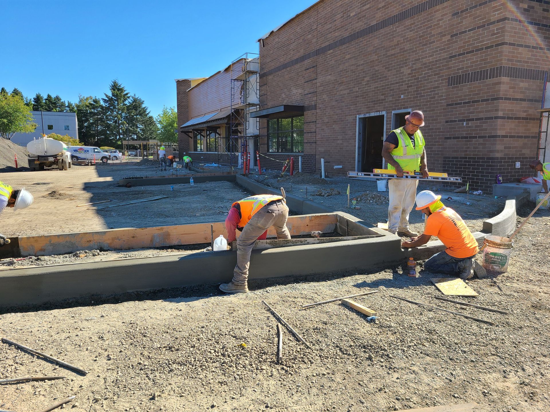 A group of construction workers are working on a sidewalk in front of a building in Vancouver, WA