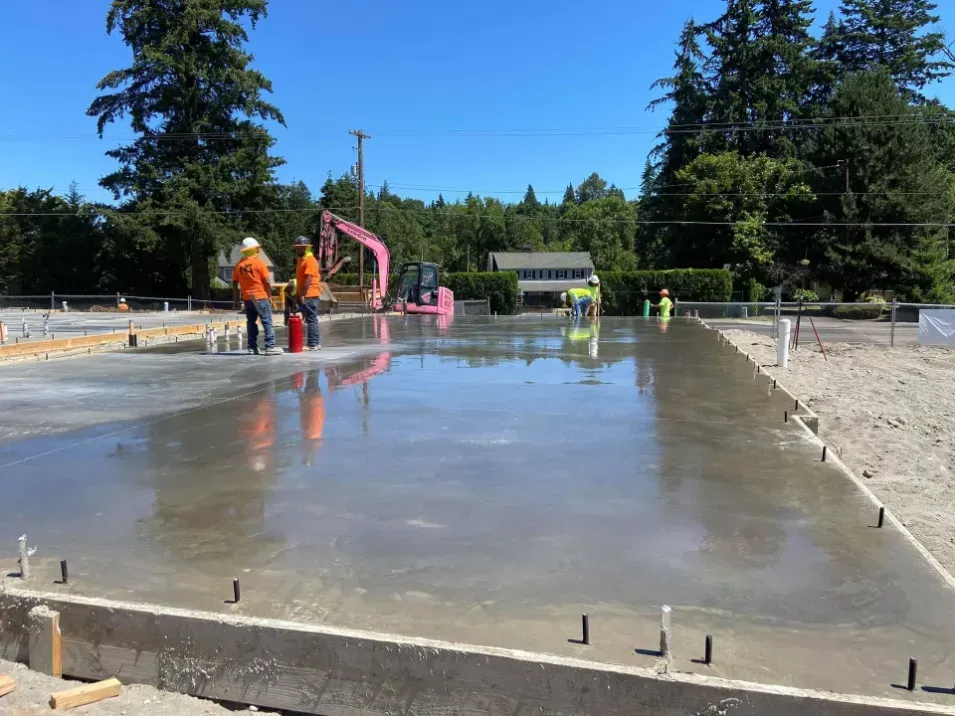 A group of construction workers are working on a concrete foundation.