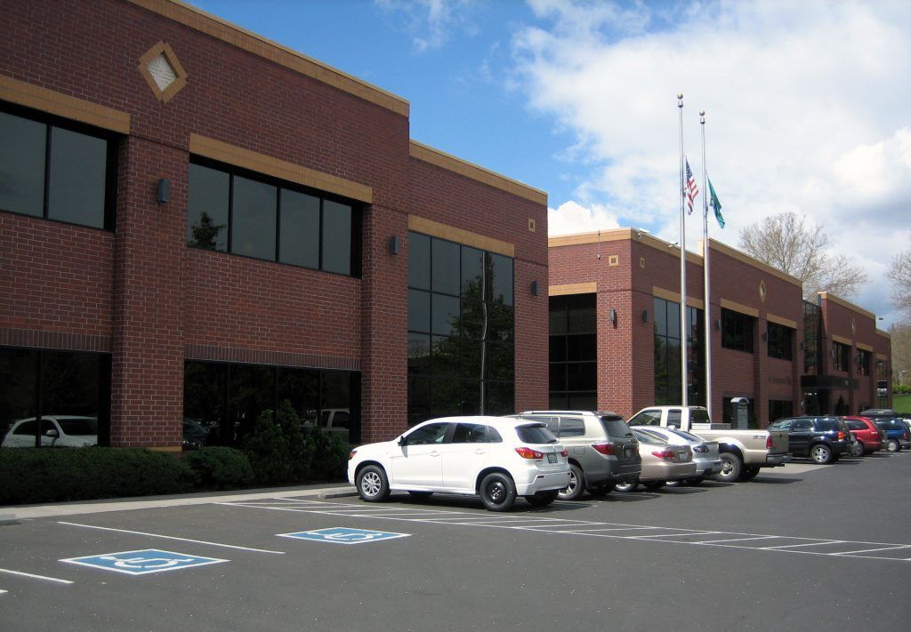 A row of cars are parked in front of a large brick building in Vancouver Washington by Nava Concrete LLC.