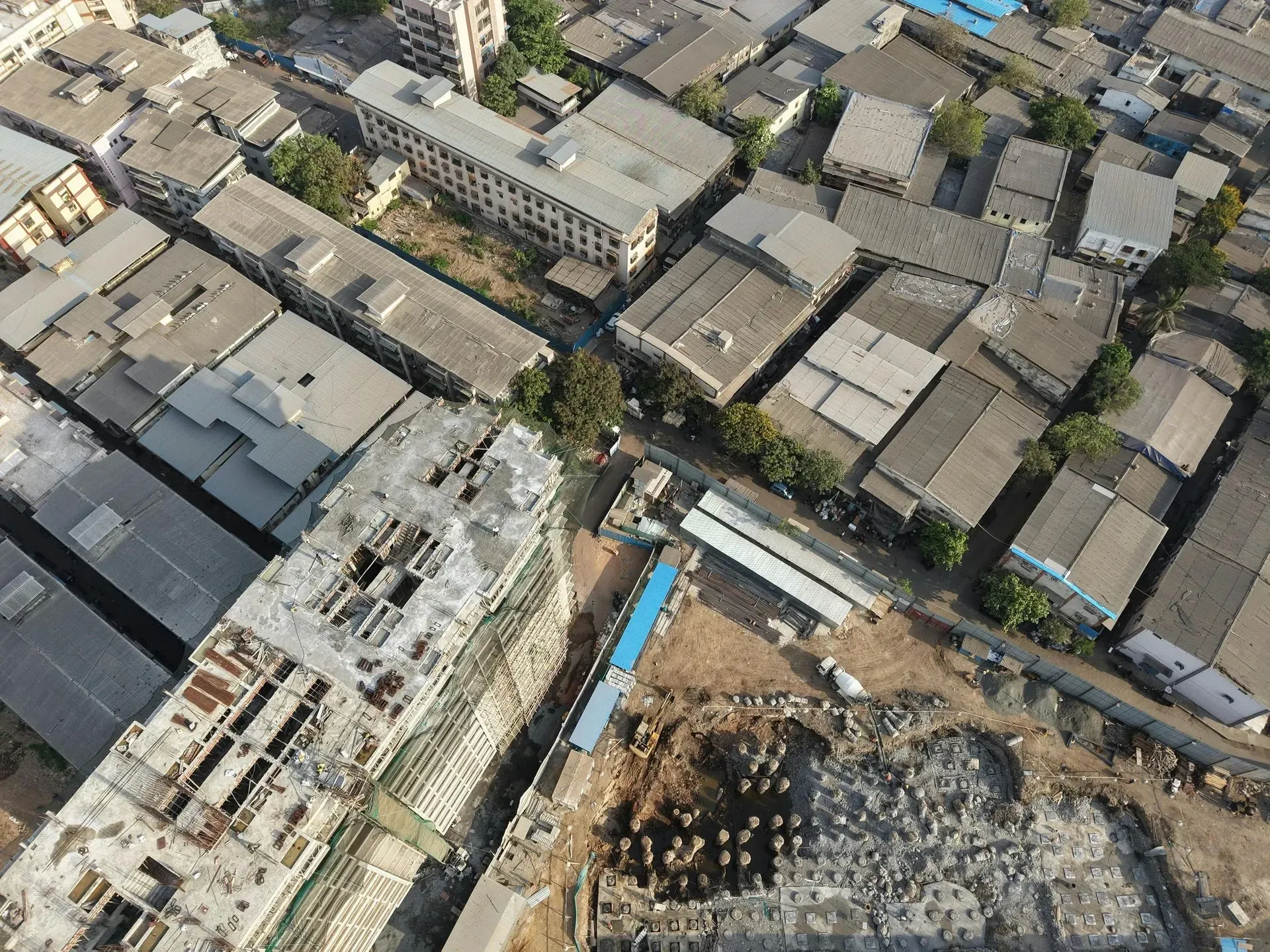 Overhead view of a dense urban area with buildings, construction site, and roads.