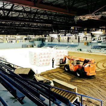 Un chariot élévateur orange est garé au milieu d'un stade