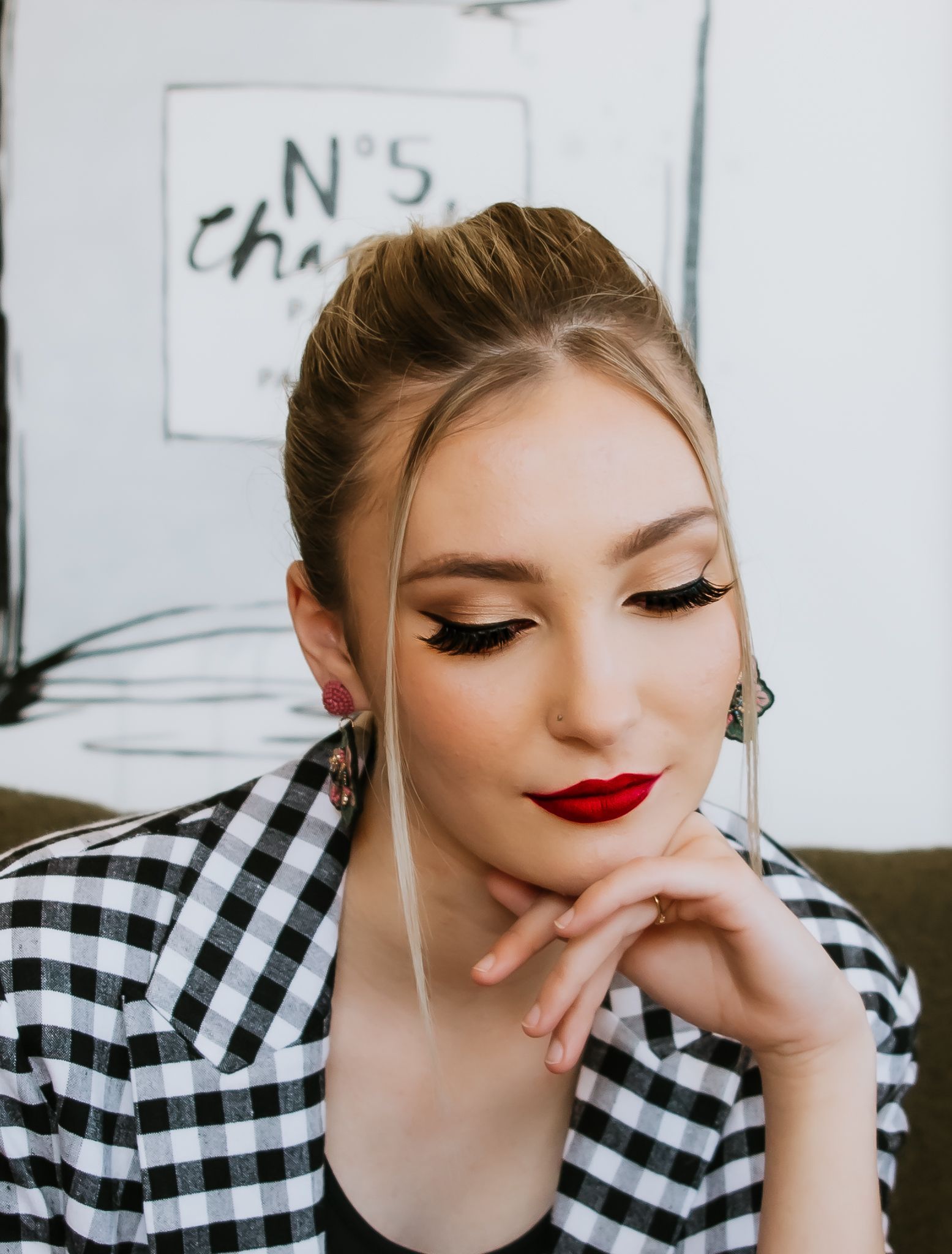 A woman wearing a plaid jacket and red lipstick is sitting on a couch — Lavie Hair & Beauty in Ciccone, NT