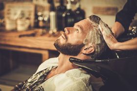 A man is getting his hair washed at a barber shop.