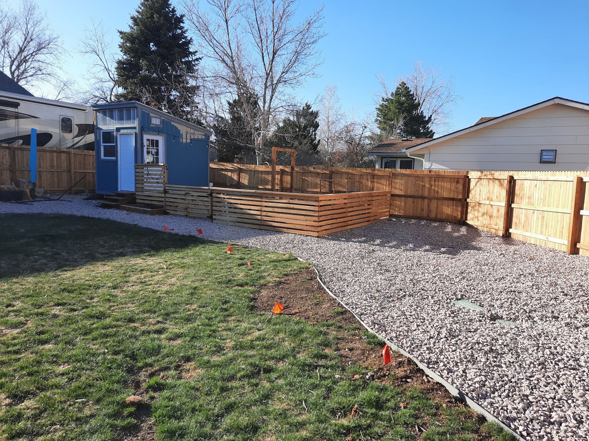 A backyard with a wooden fence and a blue shed