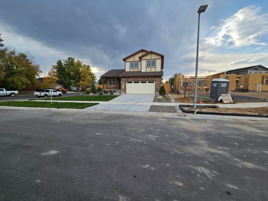 A house is being built in a residential area with trucks parked in front of it.