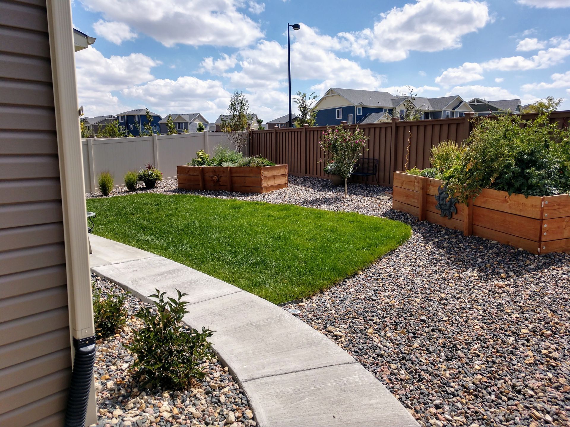 A walkway leading to a backyard with a fence and planters