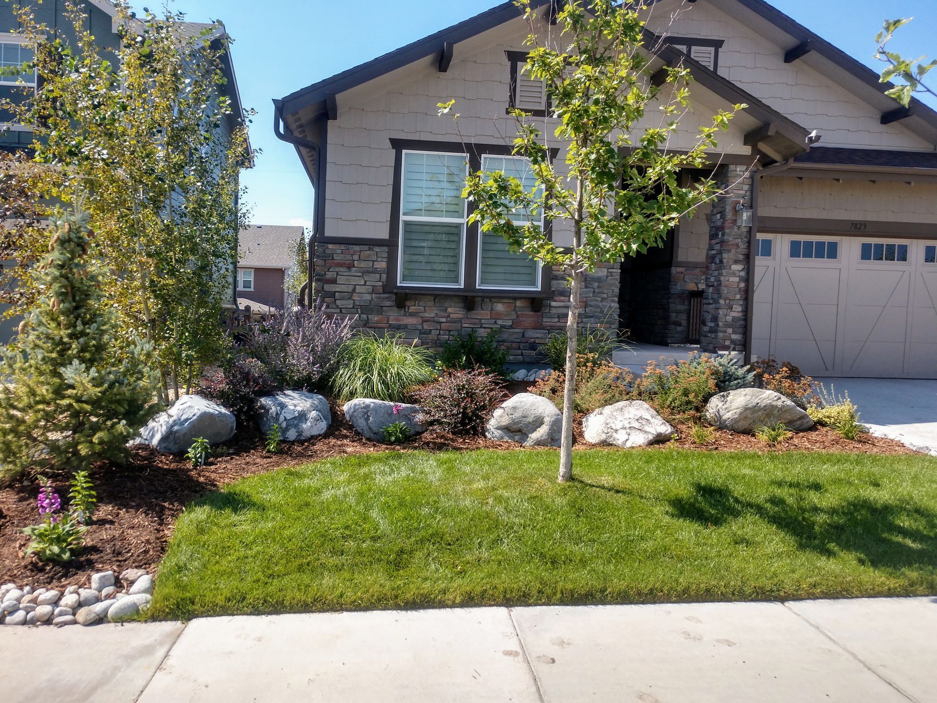 A house with a lush green lawn and rocks in front of it.