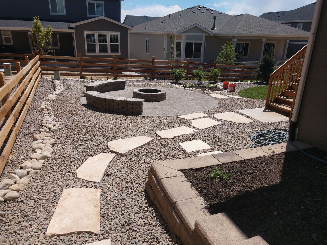 A backyard with a fire pit and a wooden fence