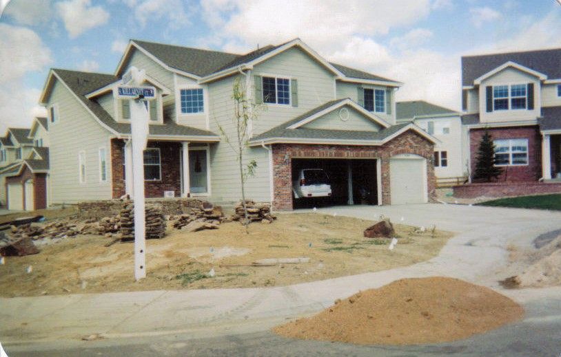 Two-story house with attached garage under construction. Exterior features brick and light-colored siding, with a street sign in the foreground.