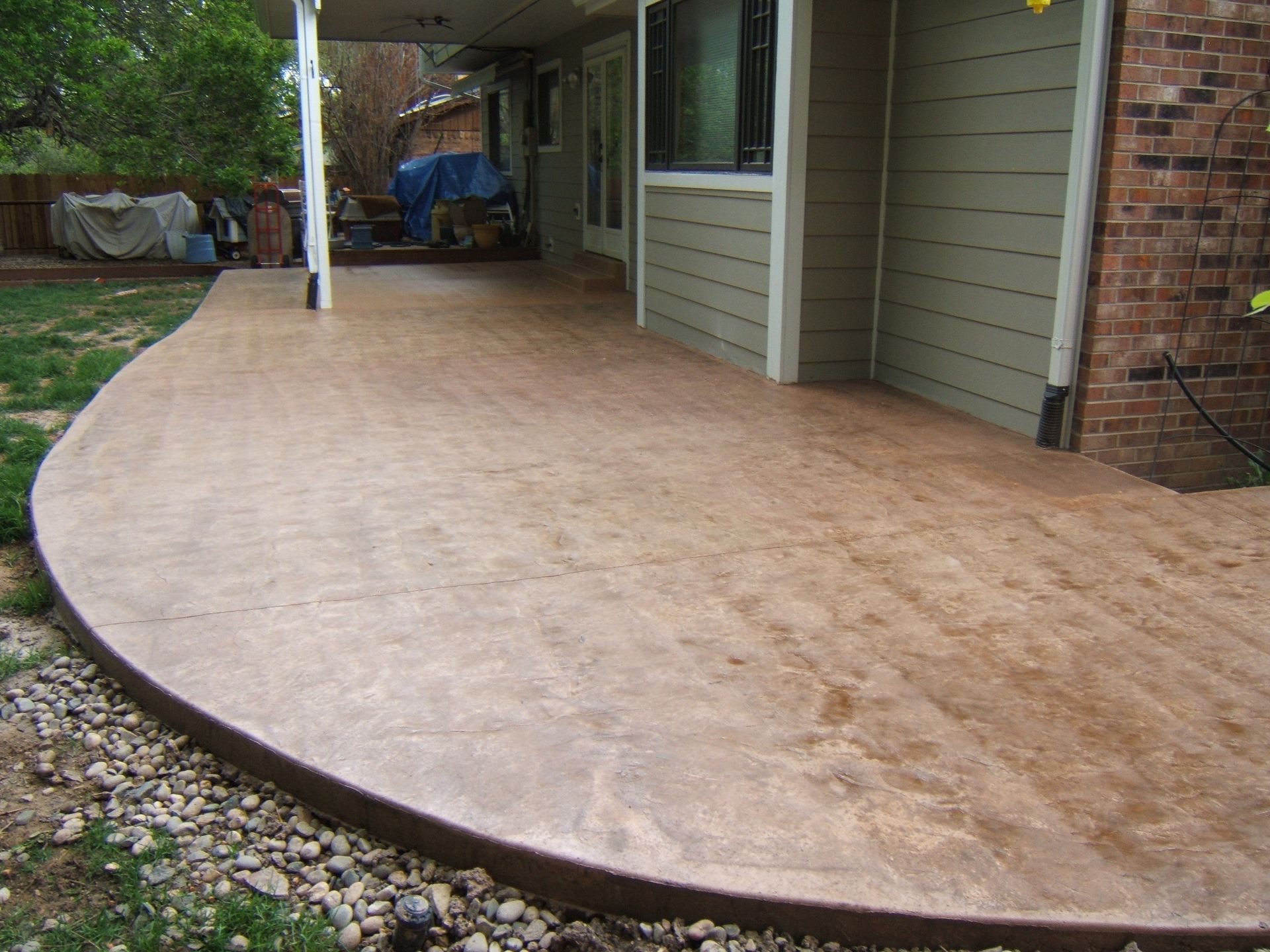 A curved concrete patio with a brick house in the background