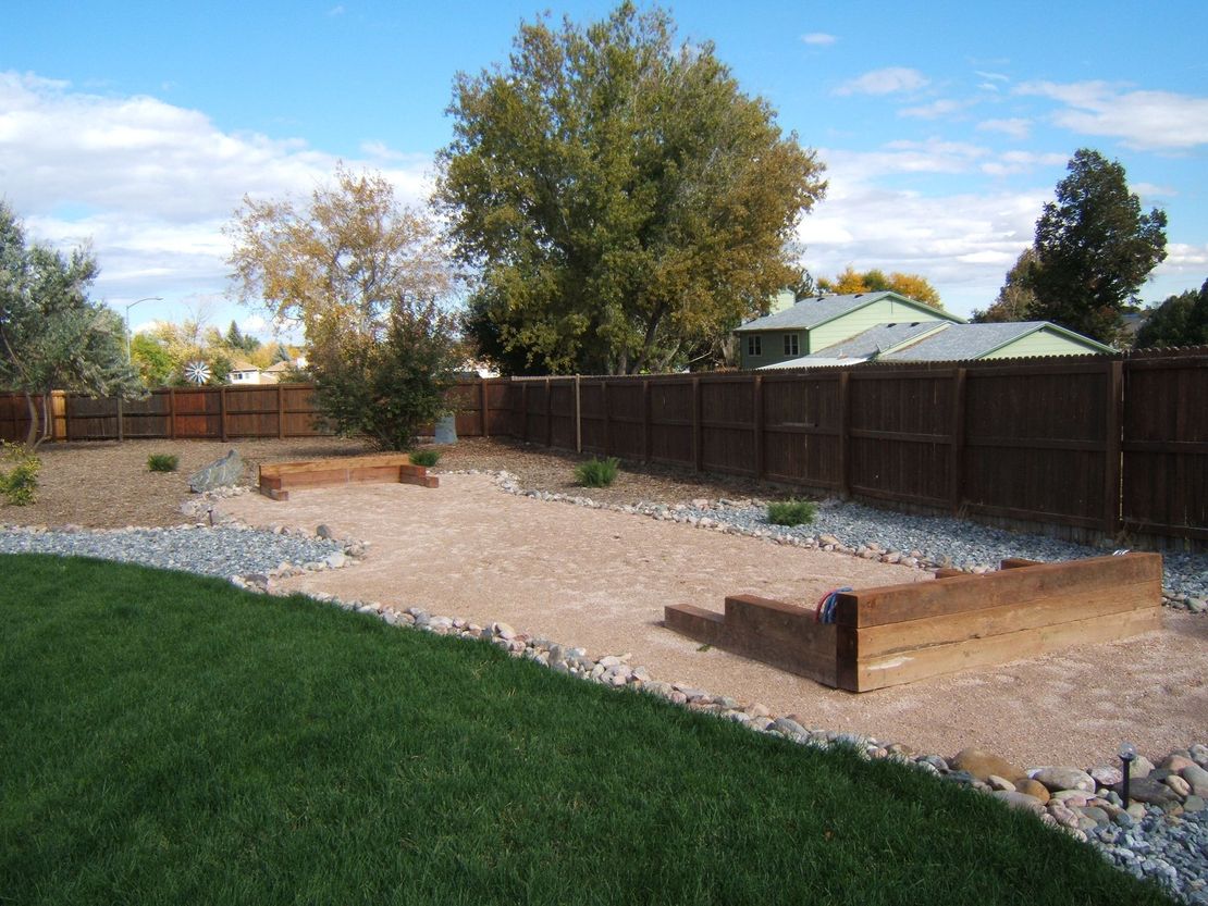 A backyard with a wooden fence and a lush green lawn