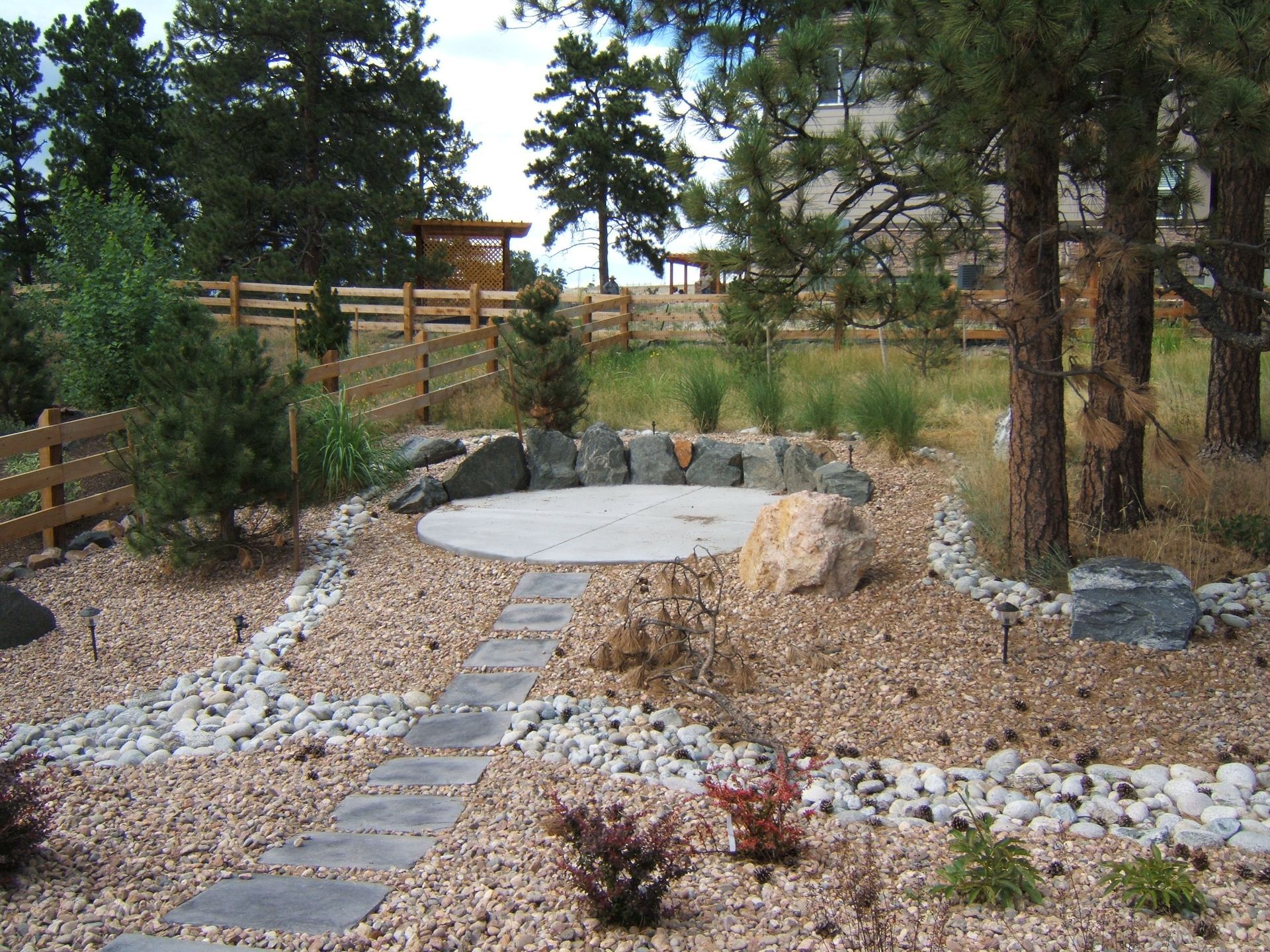 A stone path leading to a circular area surrounded by rocks and trees