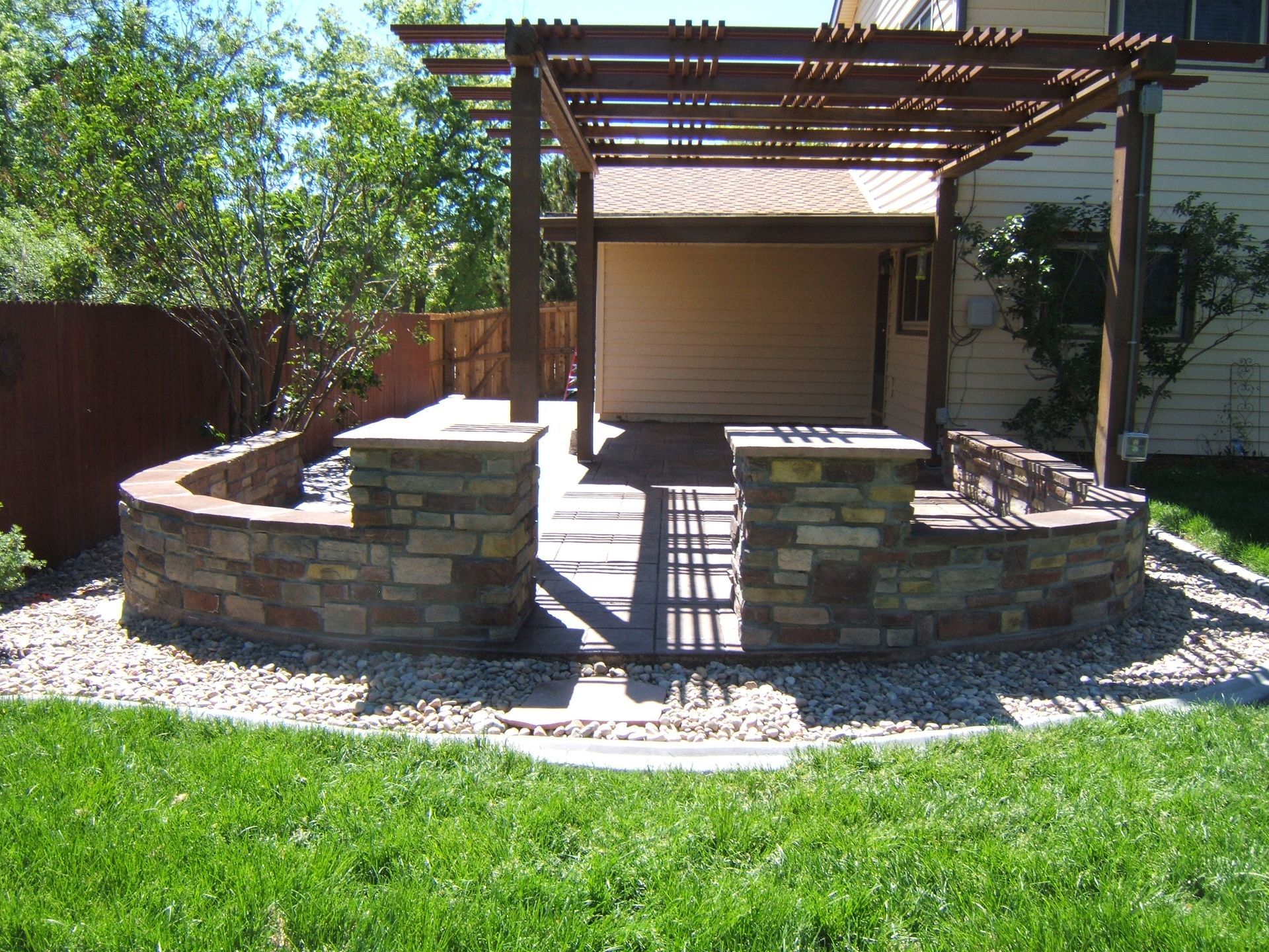 A backyard with a stone wall and a pergola