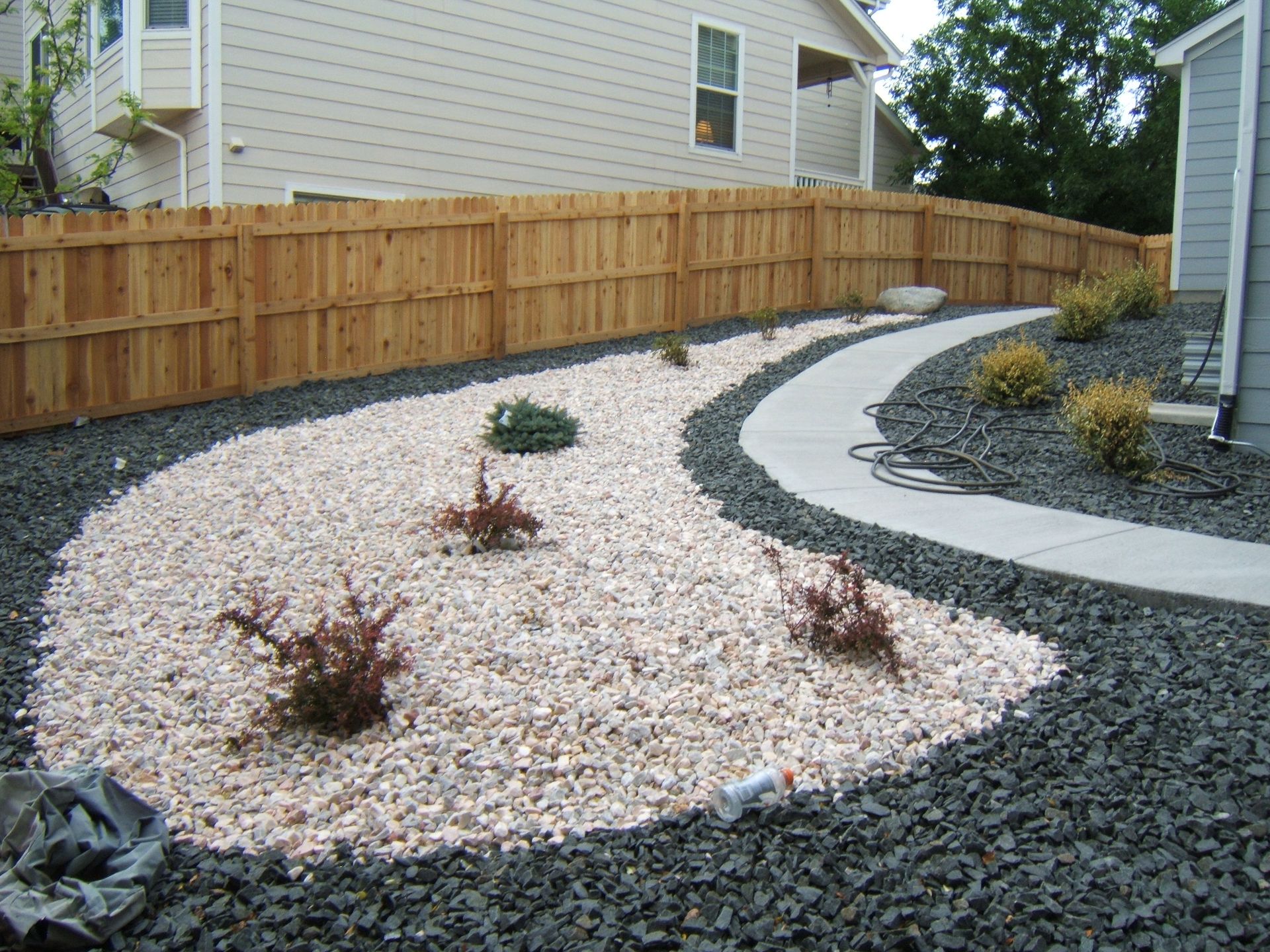 A gravel garden with a wooden fence in the background