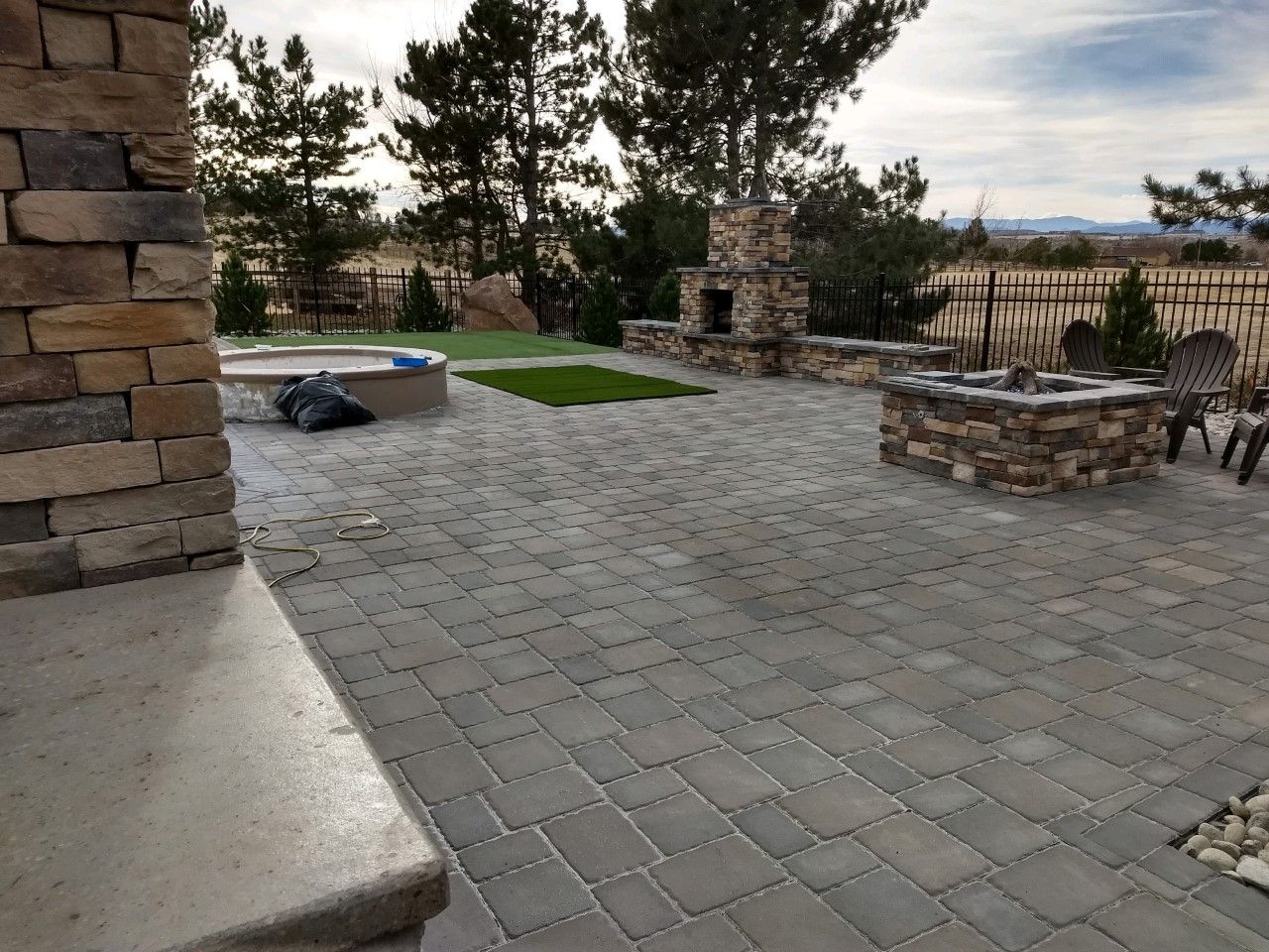 A brick patio with a fire pit and chairs