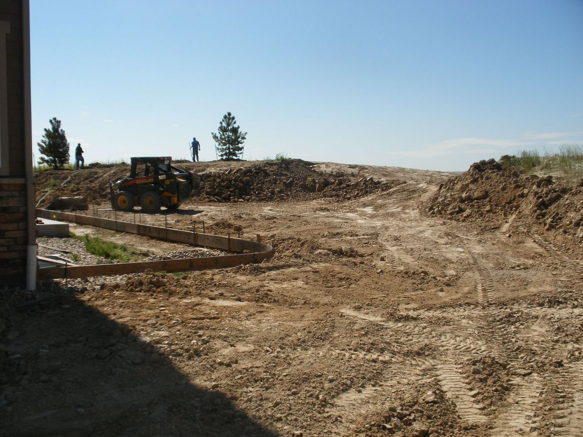 A tractor is driving down a dirt road