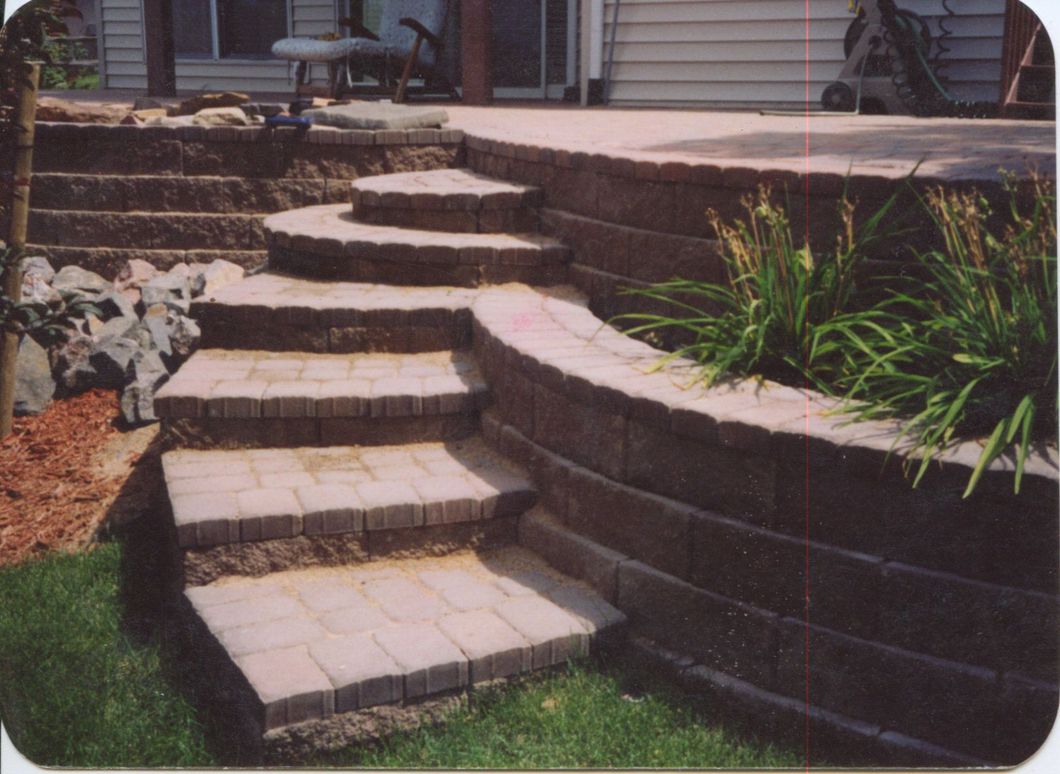 A set of stairs leading up to a patio with a house in the background