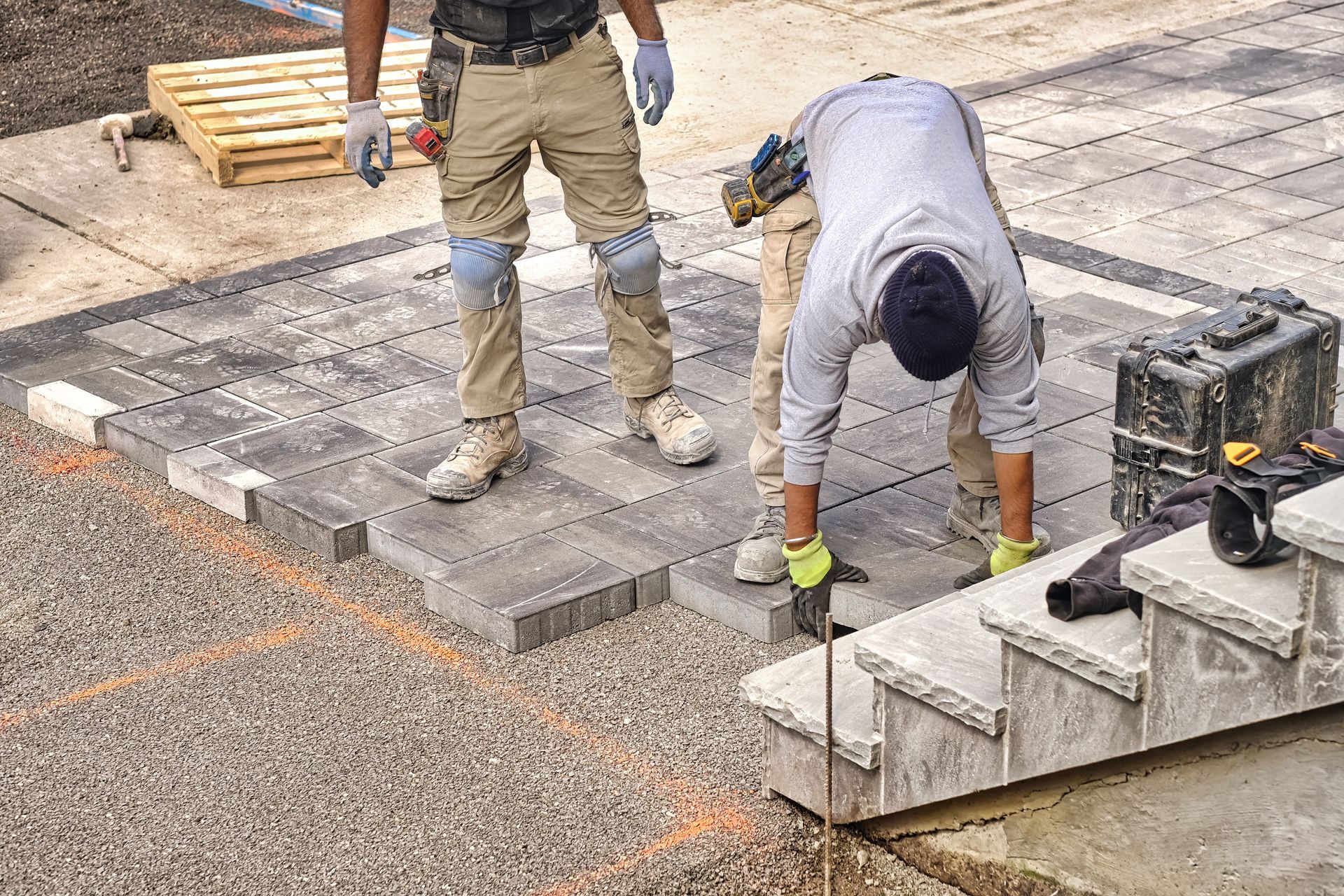 Two men are working on a concrete walkway and stairs.