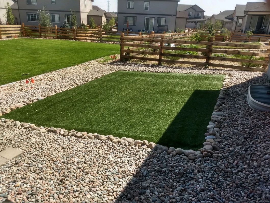 A lawn with a wooden fence and gravel surrounding it.