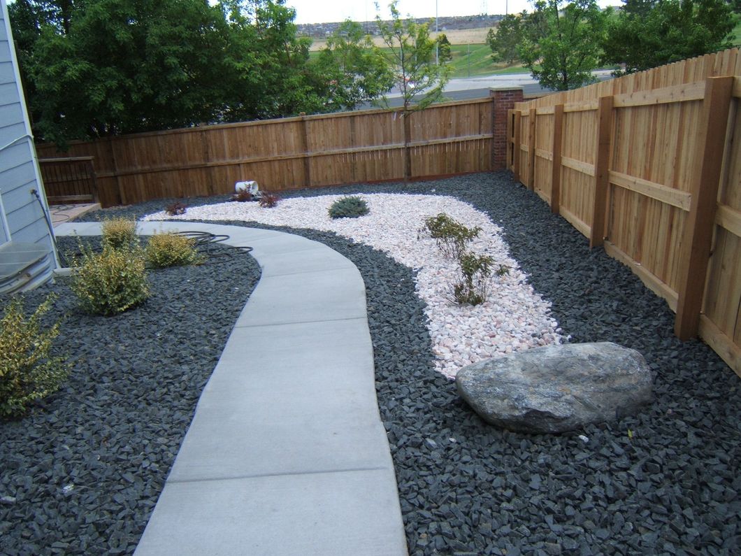 A wooden fence surrounds a concrete walkway in a backyard