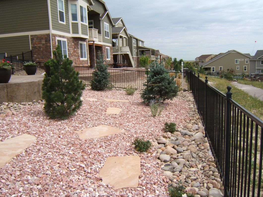 A fence surrounds a gravel area in front of a house