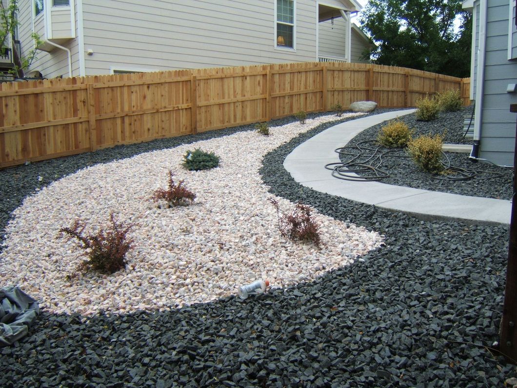 A wooden fence surrounds a gravel area in front of a house