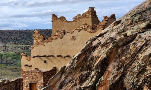A stone building is sitting on top of a rocky hill.
