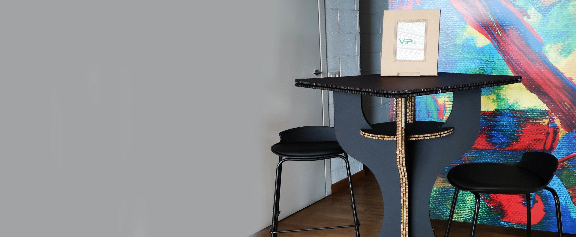 Un tavolino con due sgabelli di fronte a un'opera d'arte astratta colorata appesa a una parete.