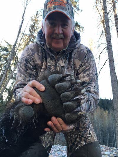 A man is holding a bear 's paw in his hands.