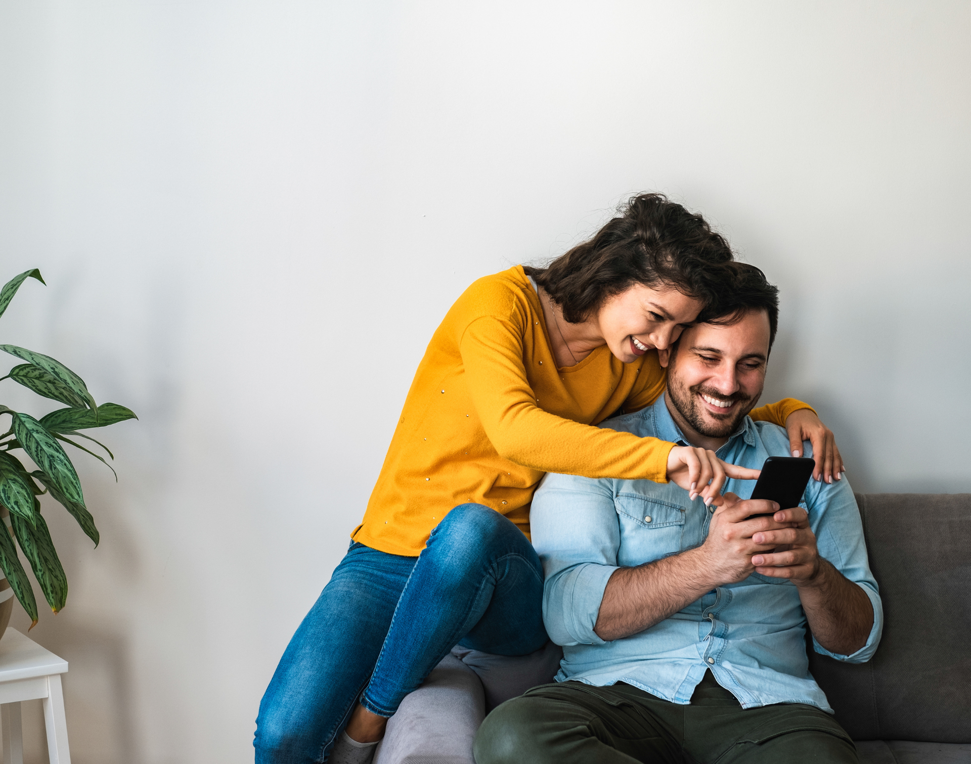 Young couple happily looking at phone together on couch