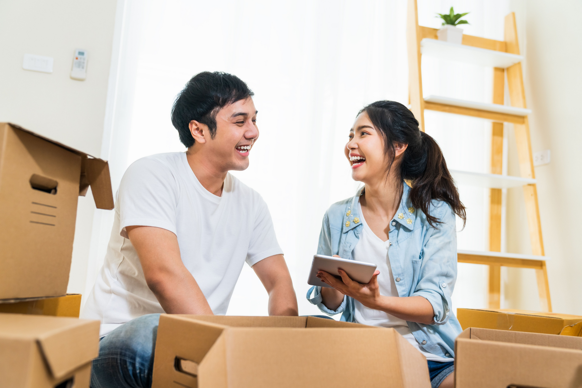 Young Asian couple packing moving boxes