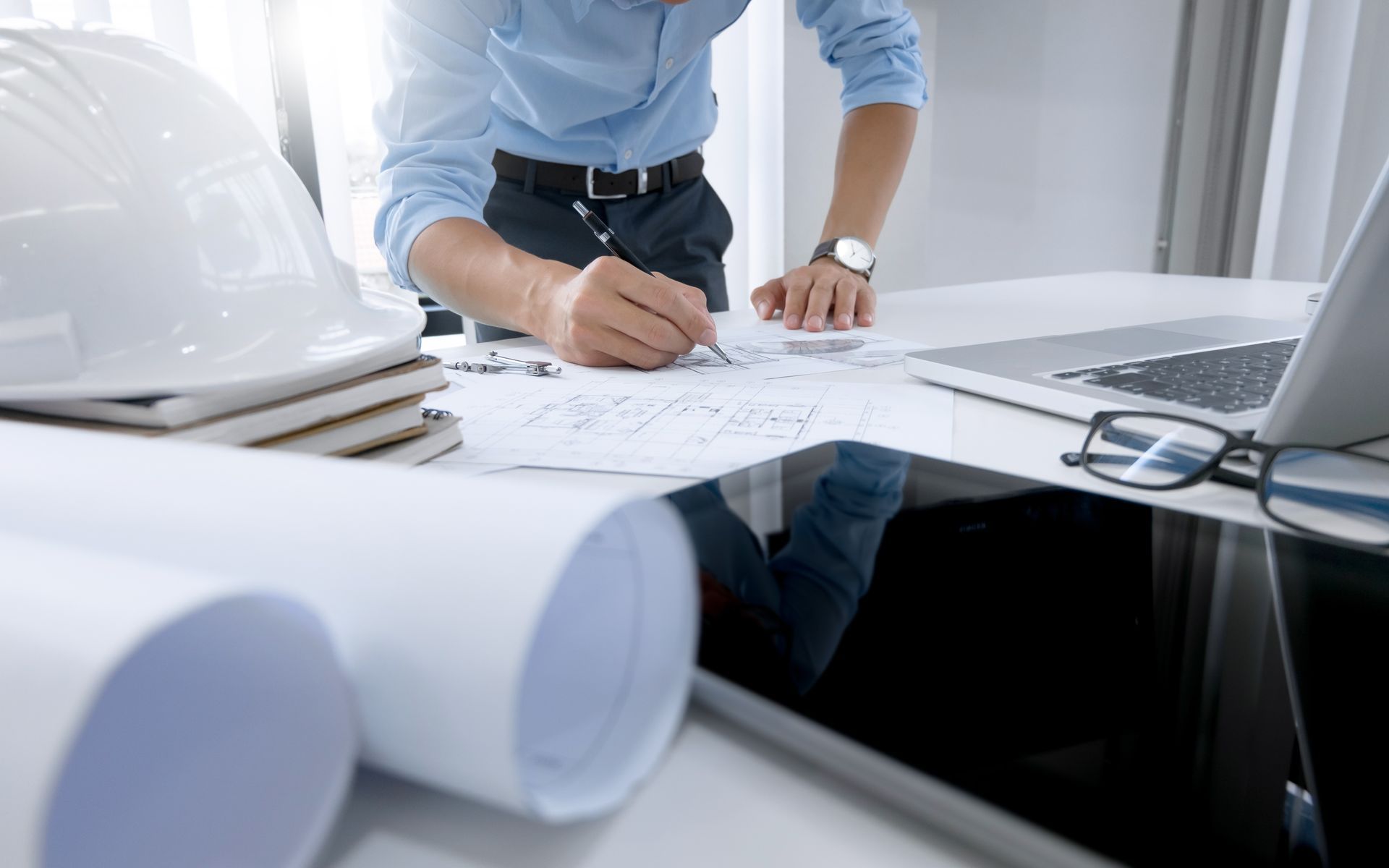A man is standing at a desk writing on a piece of paper.